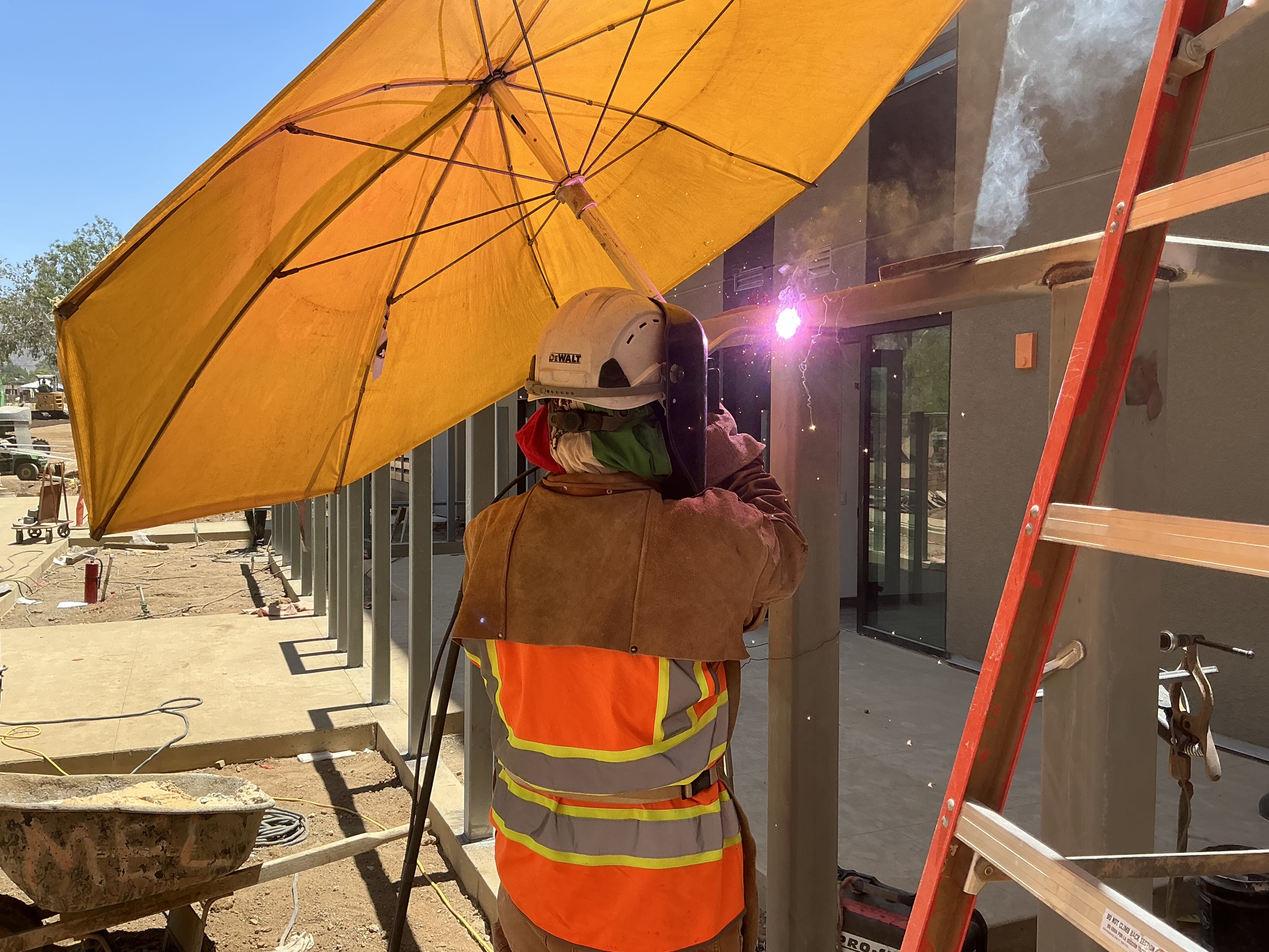 Ironworker welding under a yellow umbrella